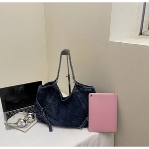 Deep blue washed denim tote bag showing its large capacity with books and tech accessories