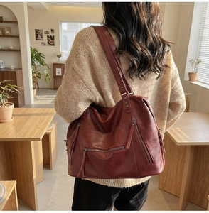 Close-up of a large vintage burgundy tote bag with silver zippers and leather texture