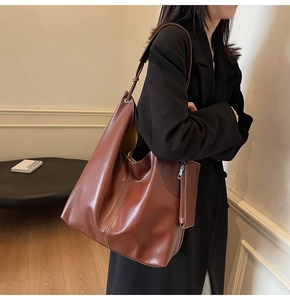 Sac fourre-tout en cuir marron foncé avec surpiqûres blanches porté par un mannequin
