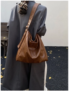 Detail view of large caramel brown hobo bag with soft lychee texture on wide strap