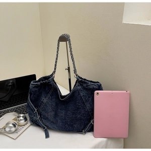 Detail of vintage washed denim shoulder bag with silver chain strap and metal buckles