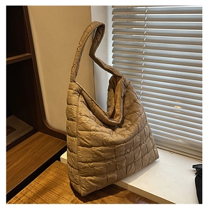 Detail of khaki quilted tote bag with square texture and soft padded fabric under natural light