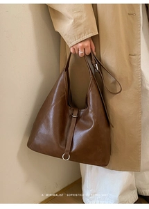 Détail d'un sac hobo marron vintage avec anneaux argentés et bandoulière réglable