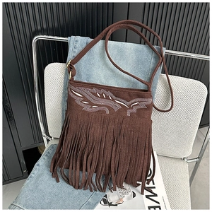 Détail d'un sac bandoulière en daim marron avec de longues franges et broderie d'ailes