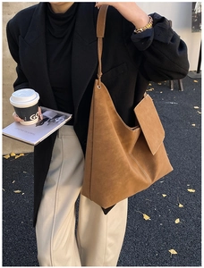 Brown suede tote bag with white stitching detail shown in an outdoor lifestyle setting