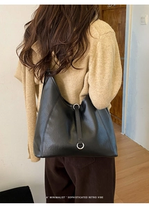 Détail d'un sac cabas minimaliste en cuir souple noir avec des anneaux en métal argenté
