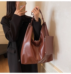 Détail d'un grand sac cabas marron avec coutures blanches et porte-monnaie assorti