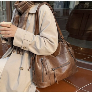 Close-up of vintage brown oil wax leather tote bag with stylish zipper tassels
