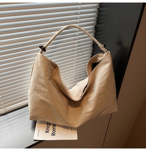 Detail of minimalist beige hobo bag with unique bead handle and soft wrinkled texture fabric