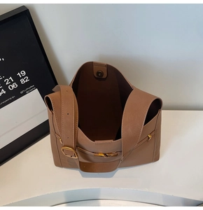Detail view of brown leather bucket bag showing magnetic clasp and gold hardware
