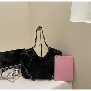 Detailed view of spacious black washed denim hobo bag shown with a tablet for size scale