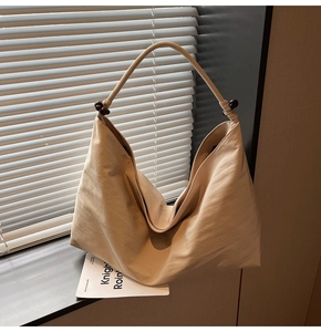 Detail of minimalist hobo bag featuring soft pleated fabric and decorative wooden beads