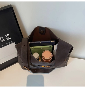 Top view of spacious interior of dark brown bucket bag showing tablets and water bottles