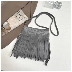 Detalle del bolso bandolera de ante gris con flecos largos y bordados de hojas blancas