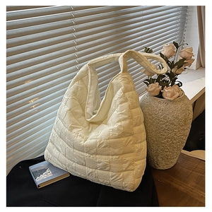 Close-up of white quilted tote bag with unique textured pleated fabric detail