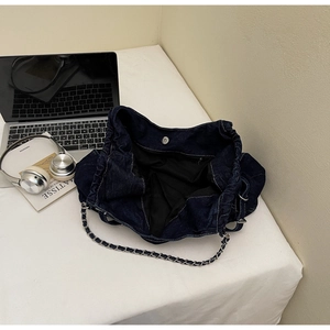 Close-up of the spacious interior with magnetic clasp and chain strap on denim tote bag