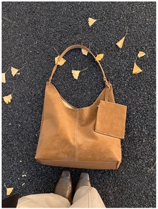 Macro shot of large vintage brown suede tote bag with white stitching detail on asphalt