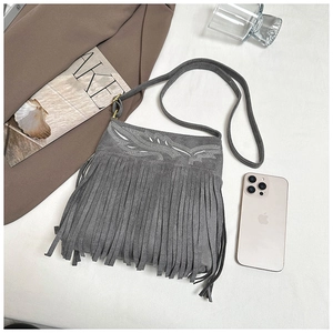 Detalle del bolso bandolera de ante gris con bordado geométrico y borlas largas y finas