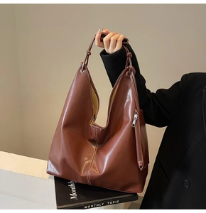 Détail d'un grand sac cabas en cuir marron avec surpiqûres blanches et pochette assortie