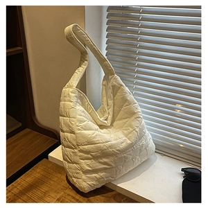 Detail of white quilted nylon tote bag showing soft textured fabric under window light