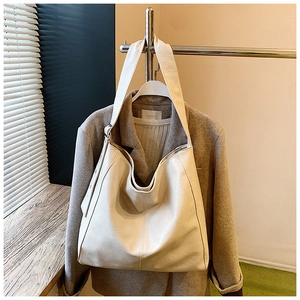 Detail view of large cream-white leather tote bag featuring matte texture and metal buckle