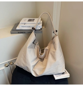 Detail of cream oversized hobo bag with dark wood decorative beads and textured fabric