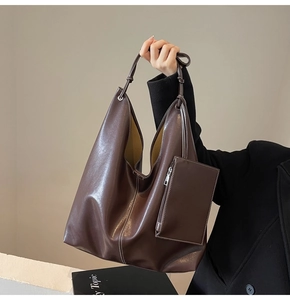 Détail du sac hobo marron foncé avec surpiqûres blanches et une pochette zippée assortie