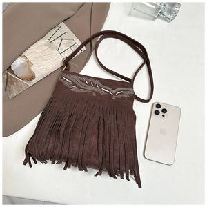 Detalle de bolso bandolera de ante marrón con flecos y bordado de ondas blancas