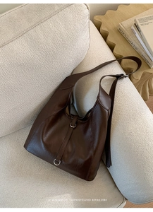 Détail d'un sac hobo en cuir souple marron foncé avec des anneaux argentés