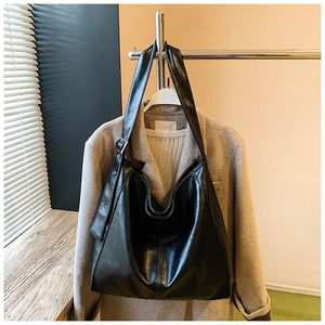 Detail view of the black leather tote bag featuring adjustable shoulder strap and buckle