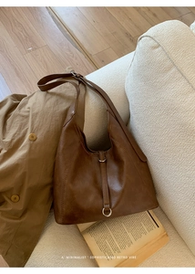 Détail du sac hobo rétro en similicuir marron foncé sur un canapé minimaliste