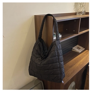Macro detail of black quilted texture on oversized puffer tote bag for women