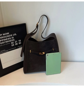 Macro view of a large brown suede bucket bag with a tablet to show its high capacity