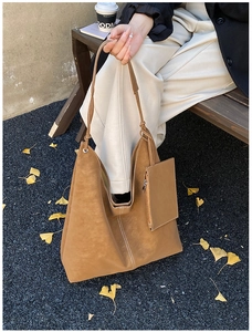 Close-up of brown suede tote bag with white stitching and matching small pouch