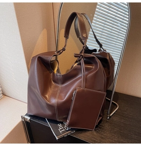 Détail d'un grand cabas en similicuir marron avec surpiqûres blanches et pochette