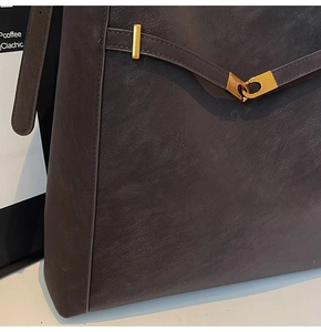 Detailed close-up of dark brown leather texture and golden metal lock on bucket bag