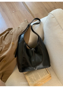 Gros plan détaillé d'un sac hobo rétro noir avec boucle argentée posé sur un canapé blanc