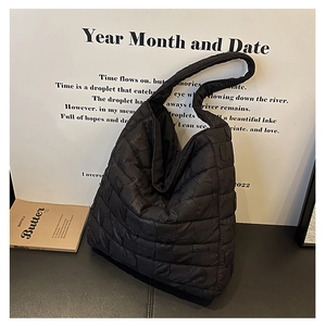 Detail of black quilted hobo tote bag featuring a soft padded texture and wide shoulder strap