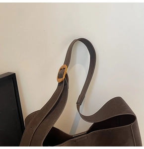 Detailed close-up of dark brown bucket bag with gold metal hardware and matte leather