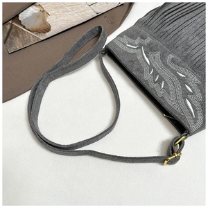 Detalle de bolso bandolera de ante gris oscuro con bordado étnico y flecos de borlas