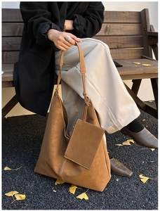 Brown frosted leather tote bag with small pouch on an autumn bench with ginkgo leaves