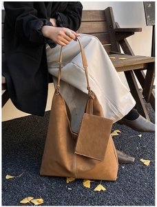 Detail of a brown suede tote bag with visible stitching and matching small square pouch