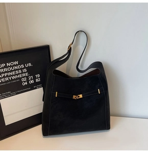 Detail of black matte leather tote bag featuring golden metal clasp and retro hardware