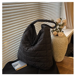 Detail of black quilted tote bag texture with diagonal stitching on a wooden table setup