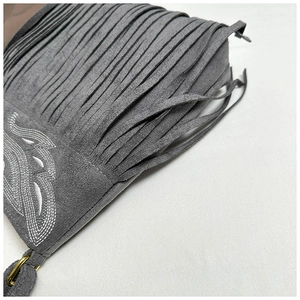 Detalle de bolso de ante gris con flecos largos y bordado blanco con diseño de ala