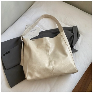 Detailed view of cream-white leather tote bag with natural wrinkled texture and wide strap