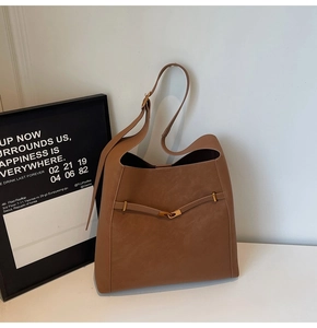 Detailed close-up of dark brown leather bucket bag with elegant gold metal buckle accent
