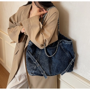 Detail of vintage washed denim tote bag showing metal chain strap and side buckle accents