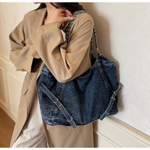 Detailed side view of washed denim tote with silver chain straps and buckle accents