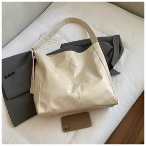 Close-up of beige tote bag showing natural wrinkled texture and wide shoulder strap